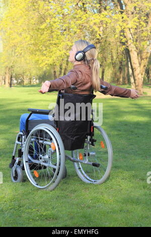 Una donna felice in una sedia a rotelle con le braccia distese Foto Stock