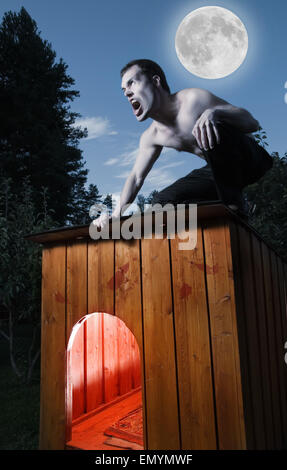 Scary uomo seduto su una cuccia e trasformando in mannaro Foto Stock