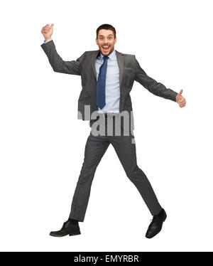 Imprenditore sorridente jumping e mostrando pollice in alto Foto Stock