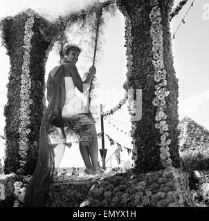 La battaglia annuale di fiori carnevale che si svolge sul canale isola di Jersey. Una donna è un andare su un altalena fatta dai fiori 5 agosto 1958. Foto Stock