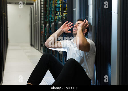 Business uomo seduto in un centro dati cercando frustrati con il sistema corrente. Egli è alla ricerca di una migliore soluzione IT. Foto Stock