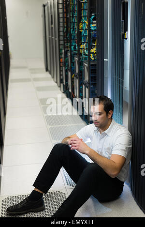 Business uomo seduto in un centro dati cercando frustrati con il sistema corrente. Egli è alla ricerca di una migliore soluzione IT. Foto Stock