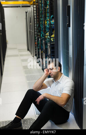 Business uomo seduto in un centro dati cercando frustrati con il sistema corrente. Egli è alla ricerca di una migliore soluzione IT. Foto Stock