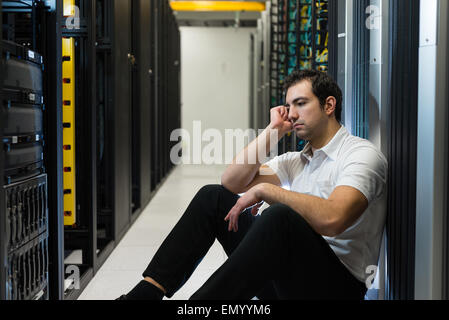 Business uomo seduto in un centro dati cercando frustrati con il sistema corrente. Egli è alla ricerca di una migliore soluzione IT. Foto Stock