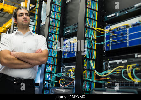 Un felice datacenter manager in posa davanti il data center rack di apparecchiature. Foto Stock