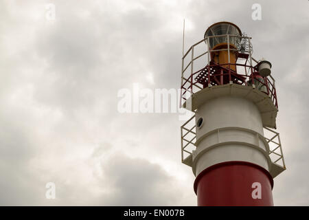 Il bianco e il rosso faro contro un grigio cielo abbronzatura Foto Stock