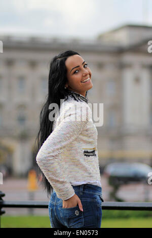 Un felice e sorridente giovane donna con lunghi capelli scuri e la carnagione di oliva fuori Buckingham Palace a Londra. Foto Stock