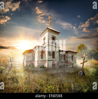 Chiesa abbandonata vicino al cimitero in un campo Foto Stock