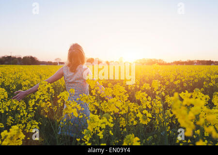 Felice giovane donna godendo di estate in campo giallo al tramonto