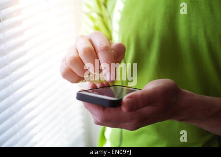 Close up di mani utilizza lo smartphone, verde t-shirt casual e mobile Foto Stock
