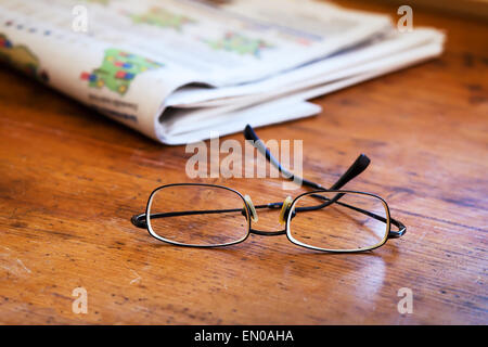Lettura dei giornali, close up di bicchieri sul tavolo di legno Foto Stock