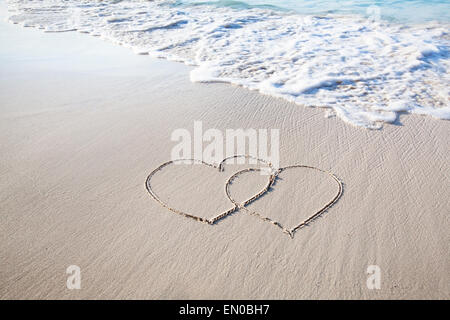 Due cuori attirato su perfettamente la sabbia bianca della spiaggia paradiso Foto Stock