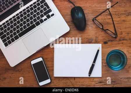 Vista superiore del tavolo in legno con notepad, laptop e smart phone Foto Stock