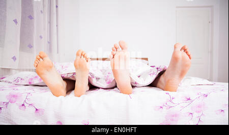 I piedi di un giovane dormendo fianco a fianco nel letto matrimoniale Foto Stock