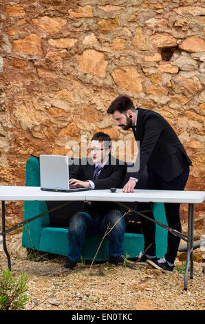 Due ragazzi intorno ad una scrivania in un ufficio di grunge, un concetto di fallimento Foto Stock
