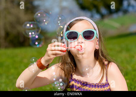 Una bambina facendo bolle di sapone in natura Foto Stock