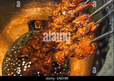 Primo piano del pollo tikka spiedini cottura su spiedini indiano forno tandoori Foto Stock