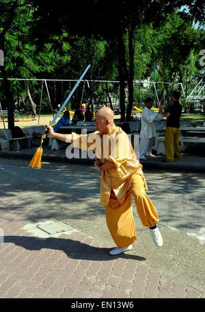 Bangkok, Thailandia: tailandese uomo brandisce una spada di eseguire il Tai Chi esercita nel Parco Lumphinee Foto Stock