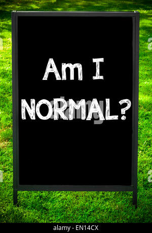 Io sono normale? Messaggio sul marciapiede di blackboard segno contro erba verde dello sfondo. Copia dello spazio disponibile. Concetto di immagine Foto Stock