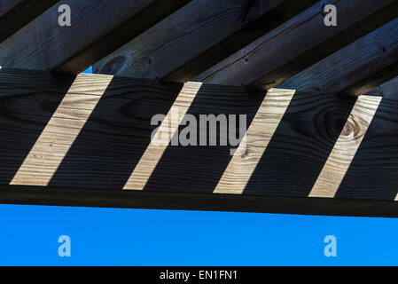 Travi di legno contro il cielo in un gioco di luci e di ombre Foto Stock