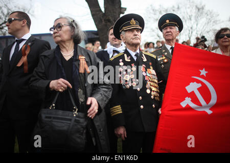 Torgau, Germania. Xxv Aprile, 2015. Un ex sovietica veterano indossa il suo medaglie detiene una bandiera nel corso delle celebrazioni per il settantesimo anniversario dell'Elba giorno in Torgau, Germania, il 25 aprile 2015. Migliaia di visitatori si sono riuniti sabato nel nord della città tedesca di Torgau per contrassegnare il settantesimo anniversario del famoso e simbolico agitando a mano di americani e soldati sovietici durante la II Guerra Mondiale su una rovina ponte che attraversa il fiume Elba a Torgau. Credito: Zhang ventola/Xinhua/Alamy Live News Foto Stock