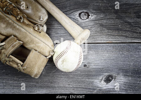 Concetto vintage del vecchio guanto indossato, bat e utilizzato il baseball su legno rustico Foto Stock