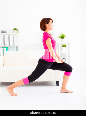 Bella giovane donna stretching sul pavimento Foto Stock