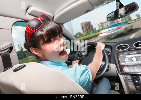 La donna in preda al panico dietro al volante della vettura. Lezioni di guida la donna dietro la ruota. Foto Stock