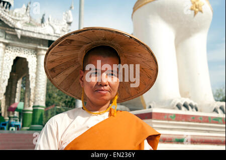 Ritratto di una monaca buddista che indossa una vasta colmato cappello di paglia davanti al tempio buddista Mandalay MYANMAR Birmania Foto Stock