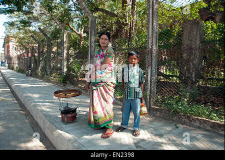 Signora indiana indossando sari colorati con suo figlio stare accanto al suo piccolo mobile fornello da cucina vendita di alimenti fritti Yangon Myanmar Foto Stock