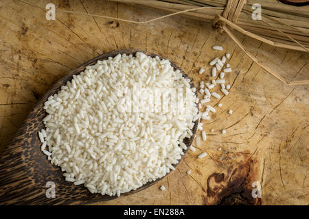 Il cucchiaio di legno il riso, i pavimenti in legno marrone, riso al gelsomino, superficie. Foto Stock