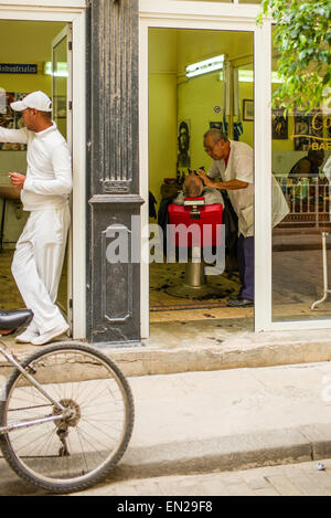 Barbiere cliente di rasatura nel suo negozio in Old Havana, Cuba. Foto Stock