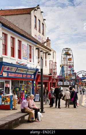 Regno Unito, Inghilterra, Yorkshire, Scarborough, Sandside, visitatori sat in sun sul banco di fronte mare Foto Stock