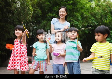 Il kindergarten insegnanti e bambini tenendo un pennello in outdoor Foto Stock