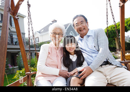 Nonni e nipoti sedersi fuori in sedia a dondolo Foto Stock