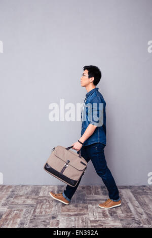 A piena lunghezza Ritratto di un youg uomo asiatico a piedi in jeans usura e borsa Foto Stock