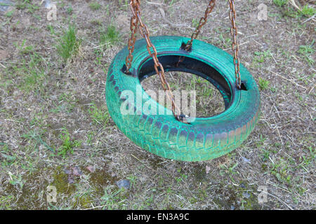 Vecchia dipinte di verde tire swing appeso in posizione di parcheggio Foto Stock