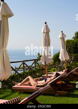 L'Italia, Ravello, Amalfi Coast, giovane a prendere il sole sulle sedie a sdraio con vista sul mare Foto Stock