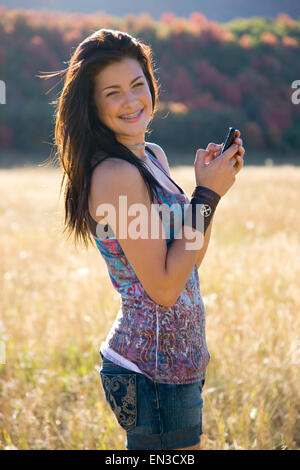 Stati Uniti d'America, Utah, sud Forcella, Ritratto di ragazza adolescente (16-17) tenendo il telefono cellulare in Prato Foto Stock