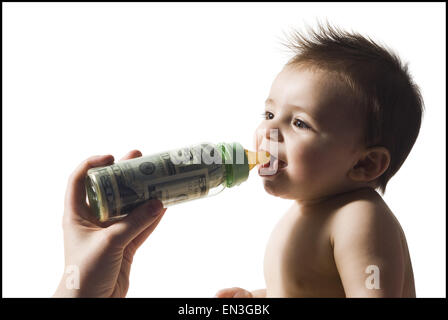 Baby di bere dalla bottiglia con valuta statunitense in esso Foto Stock