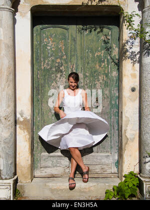 L'Italia, Ravello, donna in piedi di fronte a annaffiato porta di legno, vento donna del vestito Foto Stock