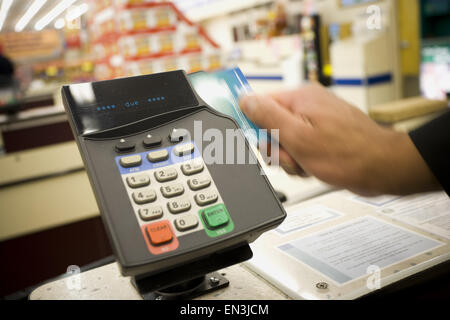 Persona scorrendo la carta di debito a macchina POS Foto Stock