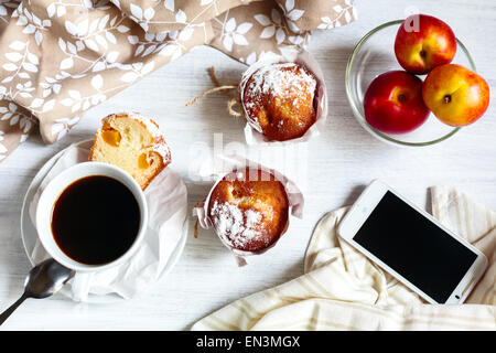 La colazione era fresca con muffin in carta cupcake titolari, caffè e frutta (pesche e pesche noci). Telefono per i social media. Foto Stock