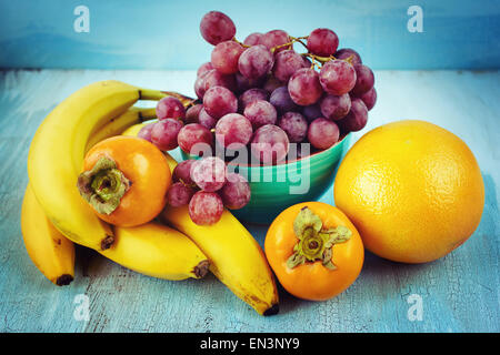 Frutti freschi in background. Banane, uva, persimmon, pompelmo. Instagram effetto vintage. Foto Stock