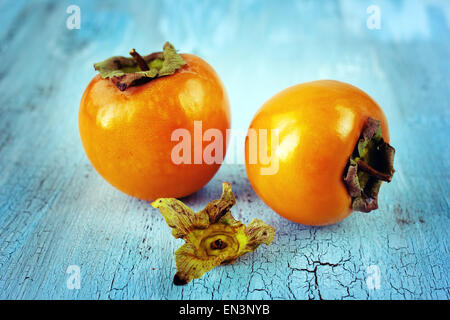 Persimmons mature con legno su sfondo blu Foto Stock