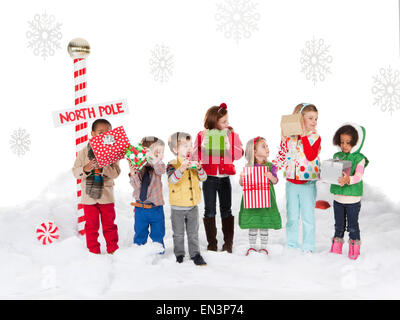 Gruppo di bambini (18-23mesi, 2-3, 4-5, 6-7) in piedi accanto al Polo Nord segno Foto Stock