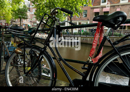 Una bicicletta appoggiata contro le ringhiere da un canale di Amsterdam Olanda Paesi Bassi Europa Foto Stock