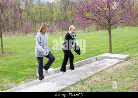 Due donne a salire le scale all'aperto a parlare e tramite cellulare. Foto Stock