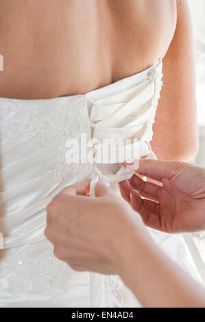 Primo piano della parte posteriore di spose abito da sposa corsetto essendo allacciato Foto Stock