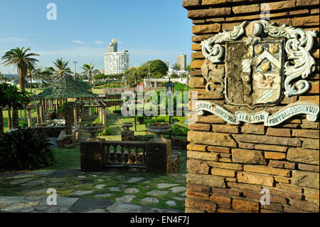 Weathered emblema sulla parete del verde giardino sommerso costruito dai prigionieri di guerra sul famoso Golden Mile beachfront, città di Durban, KwaZulu-Natal, Sud Africa Foto Stock